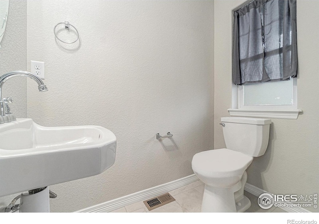 bathroom with toilet, tile patterned flooring, and sink