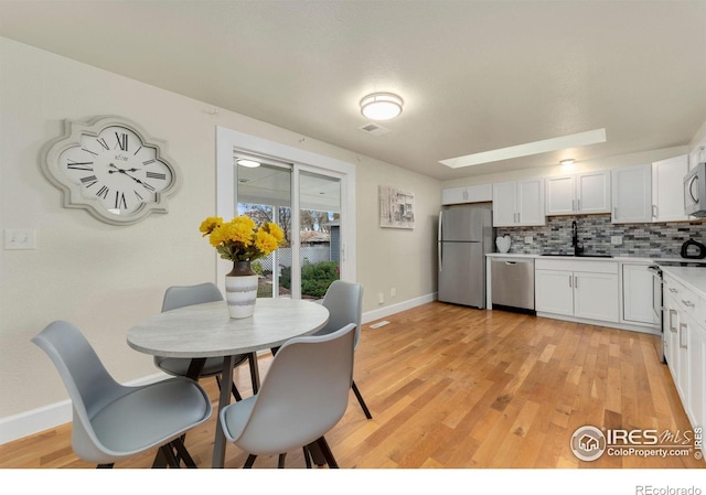 kitchen with white cabinetry, appliances with stainless steel finishes, sink, and light wood-type flooring