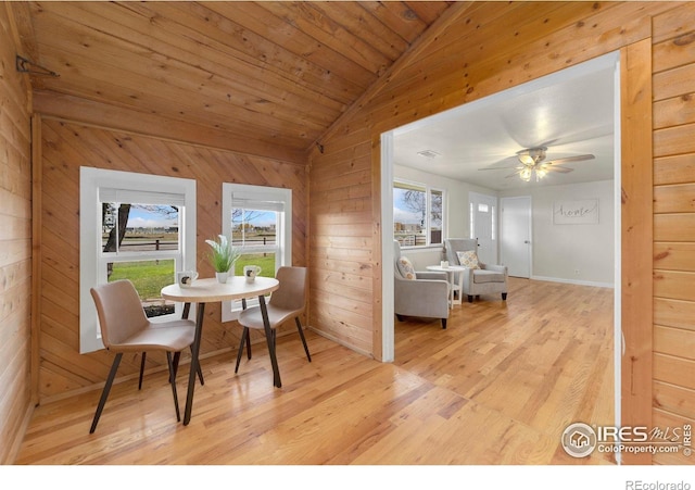 dining space with light hardwood / wood-style flooring, a healthy amount of sunlight, and wooden walls