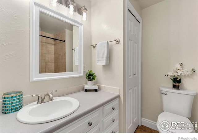 bathroom with vanity, toilet, and tiled shower