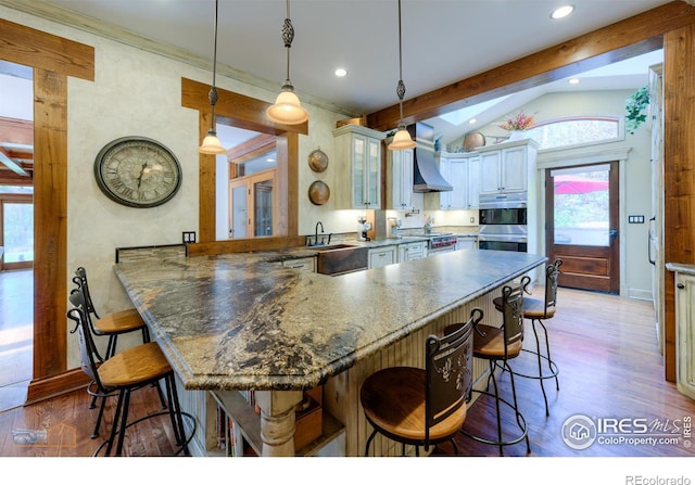 kitchen with vaulted ceiling with beams, kitchen peninsula, a breakfast bar, pendant lighting, and light wood-type flooring