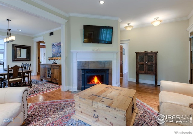 living room featuring ornamental molding, hardwood / wood-style floors, and a fireplace