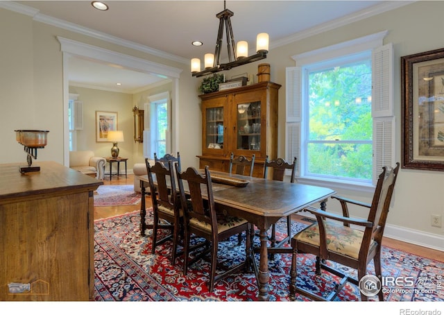 dining area featuring a notable chandelier, crown molding, and hardwood / wood-style flooring