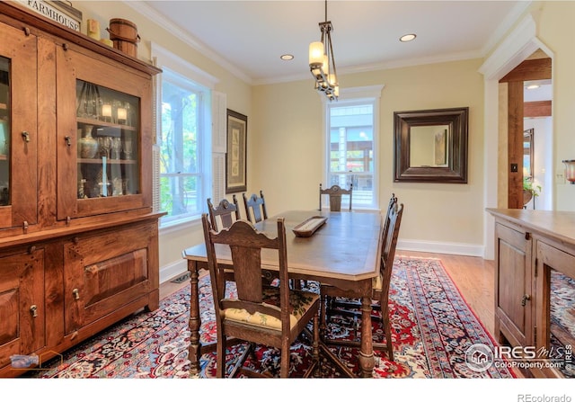 dining room featuring light hardwood / wood-style flooring, crown molding, and a notable chandelier