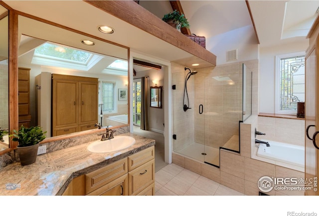 bathroom with vanity, shower with separate bathtub, tile patterned floors, and a skylight