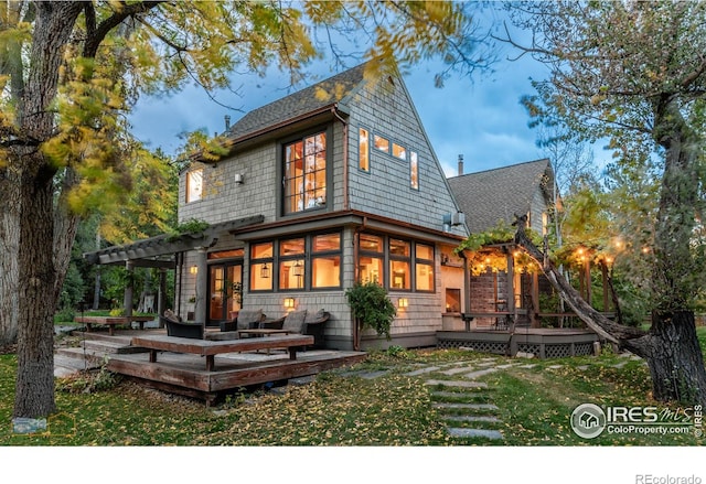 rear view of property featuring a wooden deck and a lawn