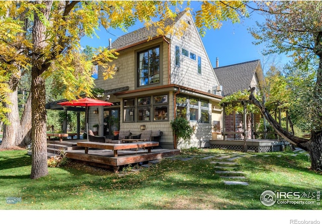 rear view of property with a wooden deck and a lawn