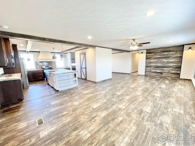 kitchen with an island with sink, dark brown cabinets, hardwood / wood-style floors, ceiling fan, and pendant lighting