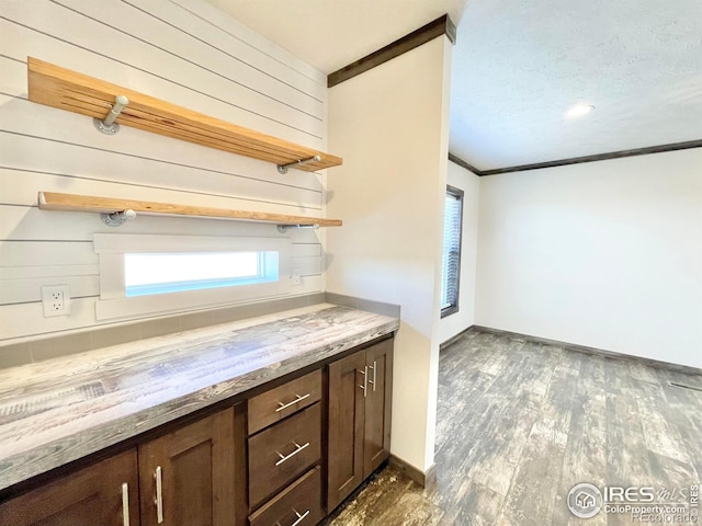 kitchen with wooden counters, ornamental molding, dark wood-type flooring, and dark brown cabinetry