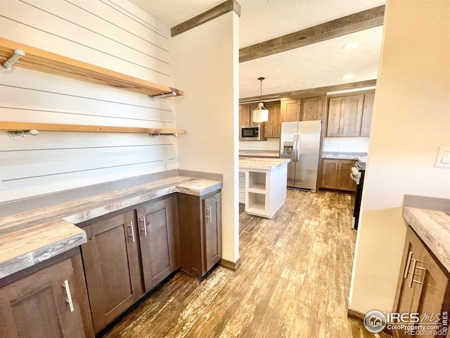 kitchen with beamed ceiling, stainless steel appliances, pendant lighting, butcher block countertops, and light hardwood / wood-style floors