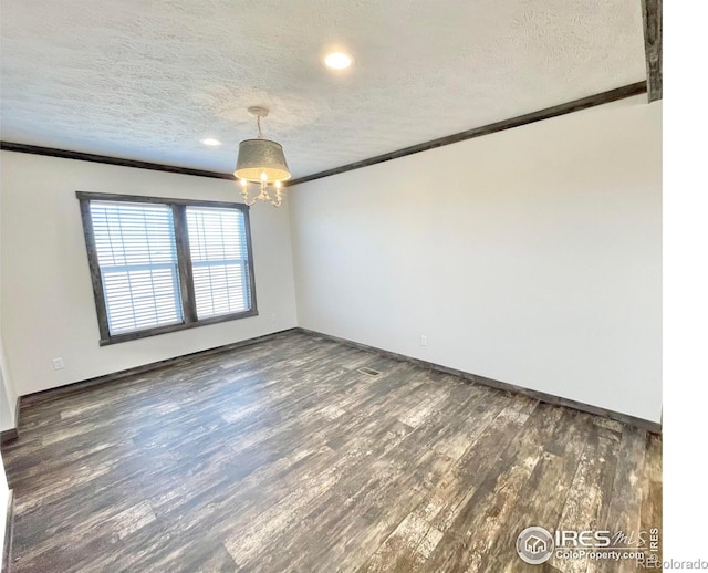 empty room featuring dark wood-type flooring, a textured ceiling, and ornamental molding