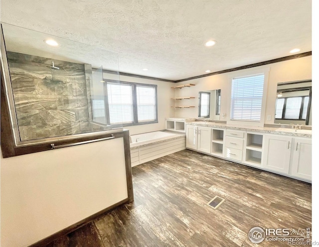 kitchen featuring a textured ceiling, dark hardwood / wood-style flooring, white cabinets, light stone counters, and ornamental molding