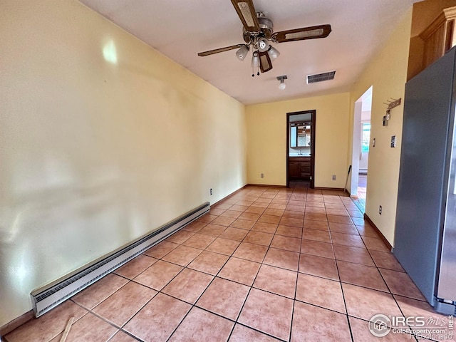 tiled empty room featuring baseboard heating and ceiling fan