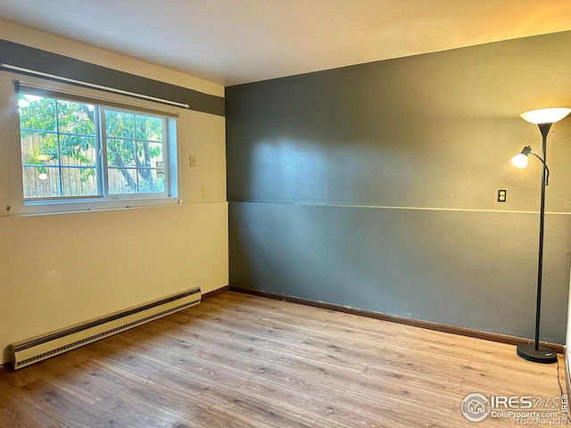 empty room with light hardwood / wood-style flooring and baseboard heating