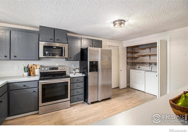 kitchen with a textured ceiling, separate washer and dryer, light hardwood / wood-style flooring, gray cabinets, and stainless steel appliances