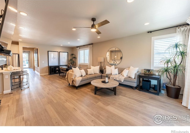 living room featuring ceiling fan, light hardwood / wood-style flooring, and plenty of natural light