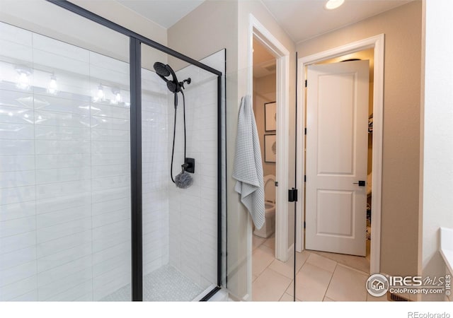 bathroom with a shower with shower door, toilet, and tile patterned flooring