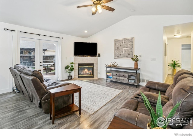 living room with wood-type flooring, french doors, a tile fireplace, ceiling fan, and lofted ceiling