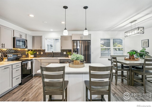 kitchen with pendant lighting, gray cabinetry, stainless steel appliances, and plenty of natural light