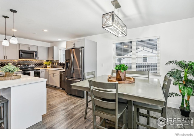 kitchen featuring light hardwood / wood-style floors, stainless steel appliances, sink, and hanging light fixtures