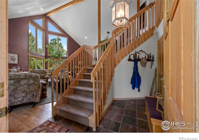 stairway featuring high vaulted ceiling, beamed ceiling, and wood-type flooring