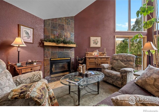 living room with high vaulted ceiling and a tile fireplace