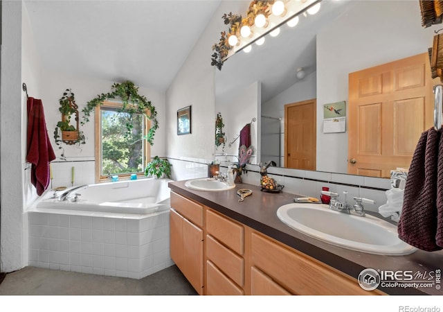 bathroom with vanity, lofted ceiling, and a relaxing tiled tub