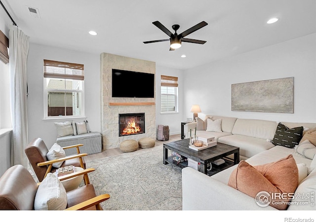 living room featuring ceiling fan, a healthy amount of sunlight, and a fireplace