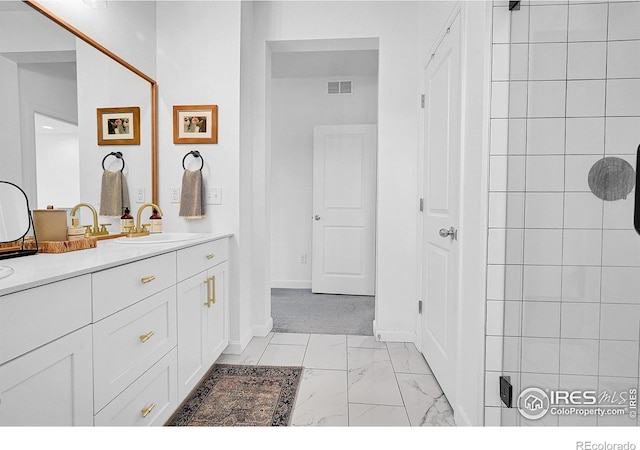 bathroom featuring tiled shower and vanity