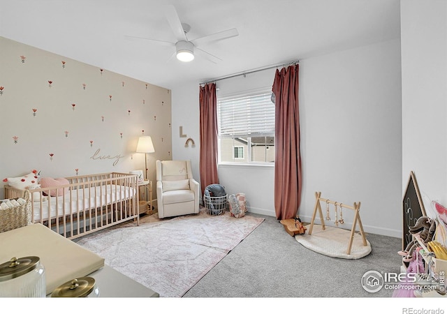 carpeted bedroom featuring a nursery area and ceiling fan