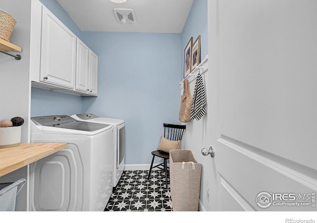 laundry area featuring cabinets, washing machine and dryer, and dark tile patterned floors