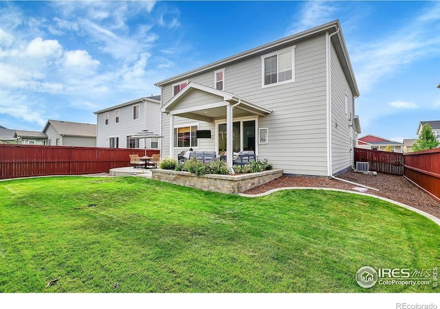 rear view of property featuring a lawn, central AC unit, and a patio area