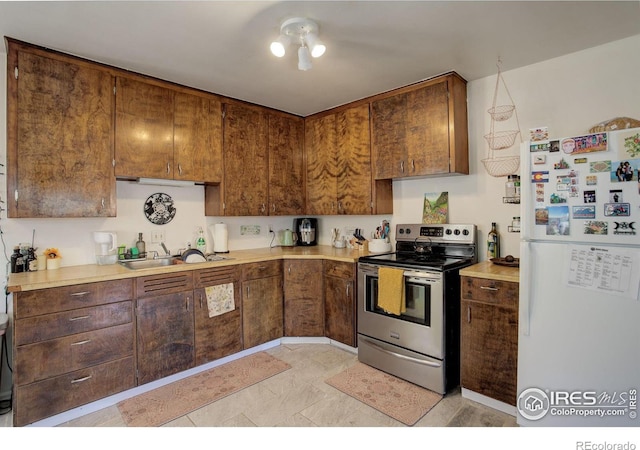 kitchen with stainless steel range with electric cooktop, sink, and white refrigerator