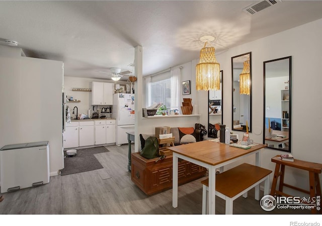 dining area featuring light hardwood / wood-style flooring, a textured ceiling, and ceiling fan