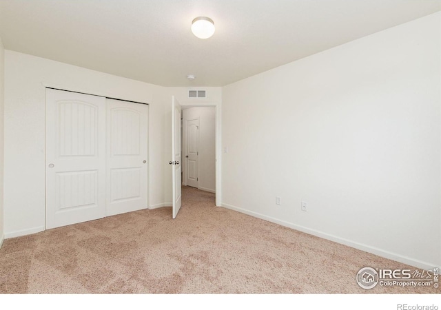 unfurnished bedroom with a closet and light colored carpet