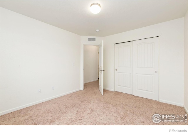 unfurnished bedroom with a closet and light colored carpet