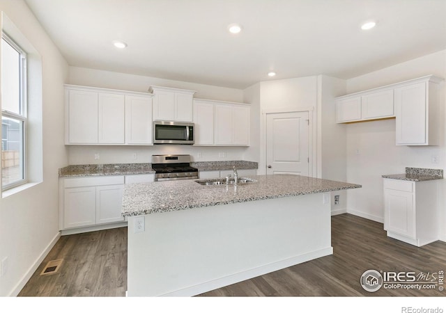 kitchen with appliances with stainless steel finishes, sink, a center island with sink, and white cabinets