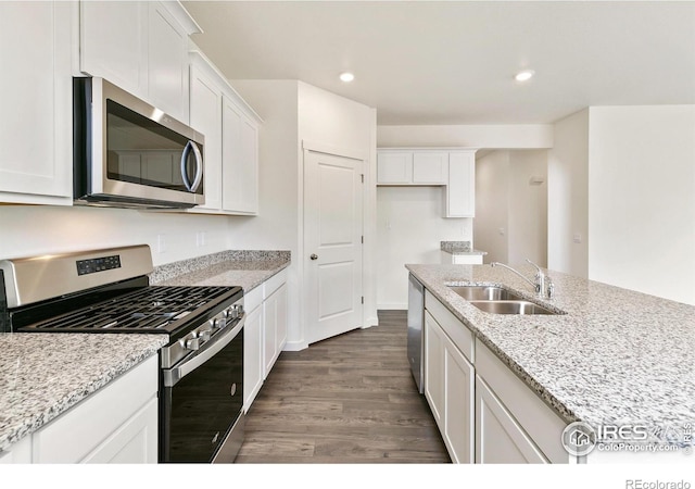 kitchen with dark wood-type flooring, sink, light stone countertops, white cabinets, and appliances with stainless steel finishes