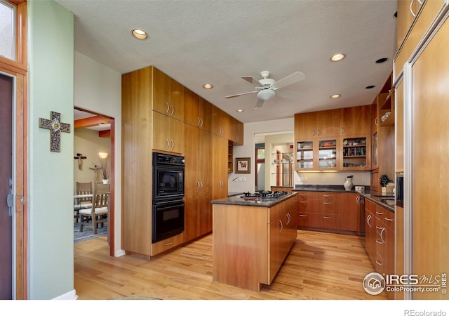 kitchen featuring a kitchen island, a textured ceiling, stainless steel appliances, and light wood-type flooring