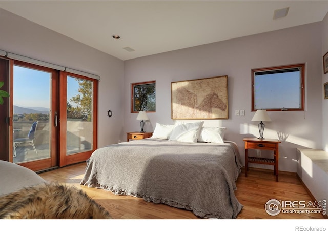 bedroom featuring light hardwood / wood-style flooring, a mountain view, access to exterior, and french doors