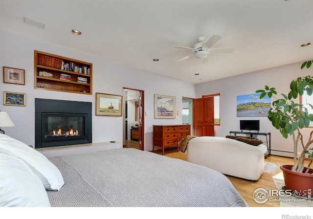 bedroom featuring light hardwood / wood-style floors, a baseboard radiator, and ceiling fan