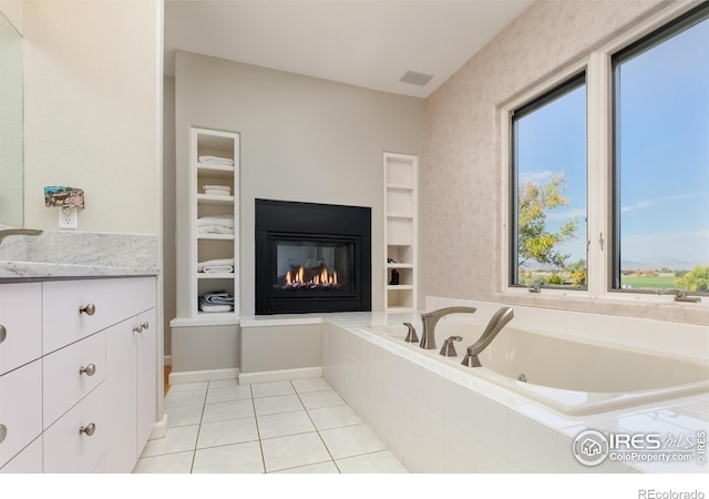 bathroom featuring vanity, a relaxing tiled tub, tile patterned floors, and built in shelves