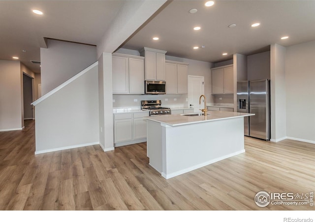 kitchen featuring stainless steel appliances, sink, a center island with sink, and white cabinets