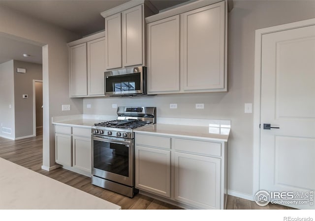 kitchen featuring hardwood / wood-style flooring, appliances with stainless steel finishes, and white cabinets