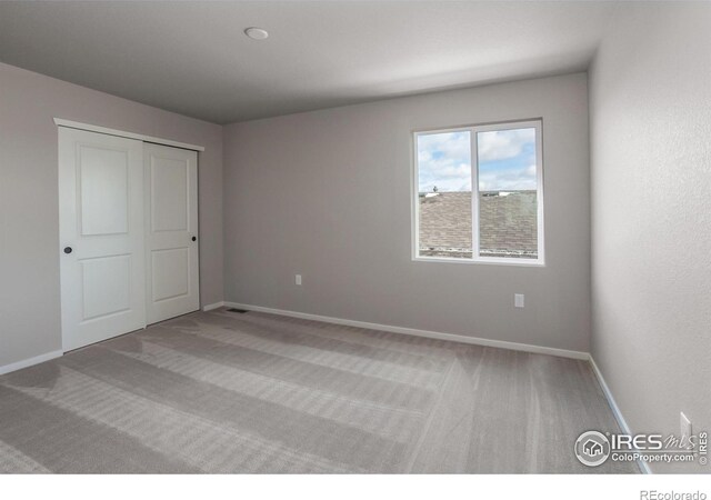 unfurnished bedroom with light colored carpet and a closet