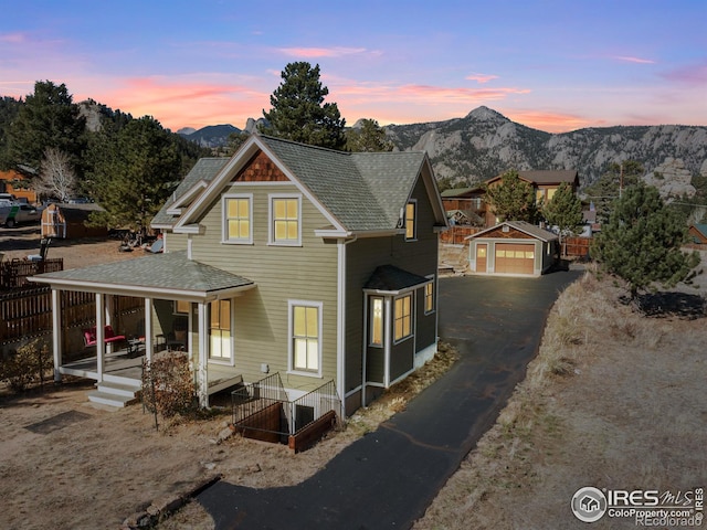 view of front facade with a mountain view, an outbuilding, a garage, and covered porch