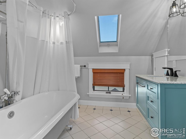 bathroom with vanity, a tub to relax in, tile patterned flooring, and lofted ceiling with skylight