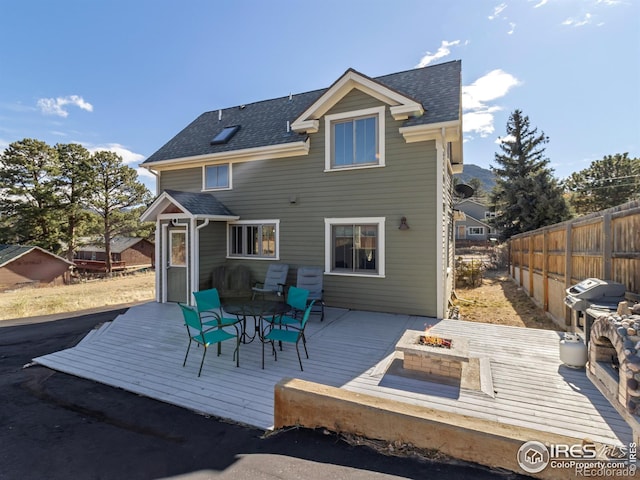 back of property with an outdoor fire pit and a wooden deck