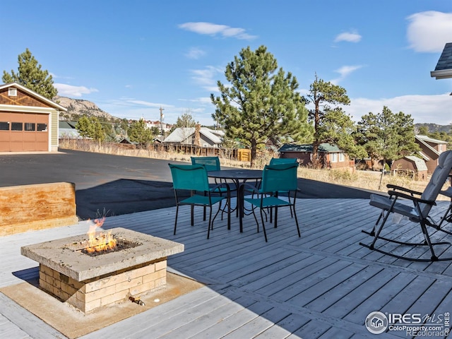 wooden terrace featuring a mountain view, an outdoor fire pit, and an outdoor structure