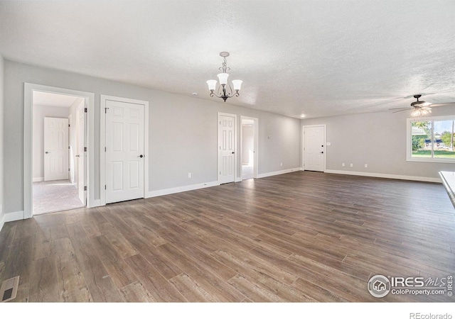 unfurnished living room with a textured ceiling, ceiling fan with notable chandelier, and dark hardwood / wood-style flooring